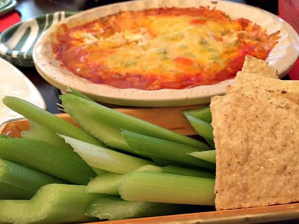 Buffalo Chicken Dip in a pan with celery sticks and chips