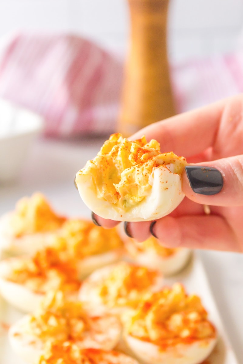 hand holding deviled egg with bite out of it