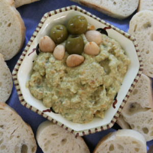 overhead shot of dish of green olive spread surrounded by baguette slices