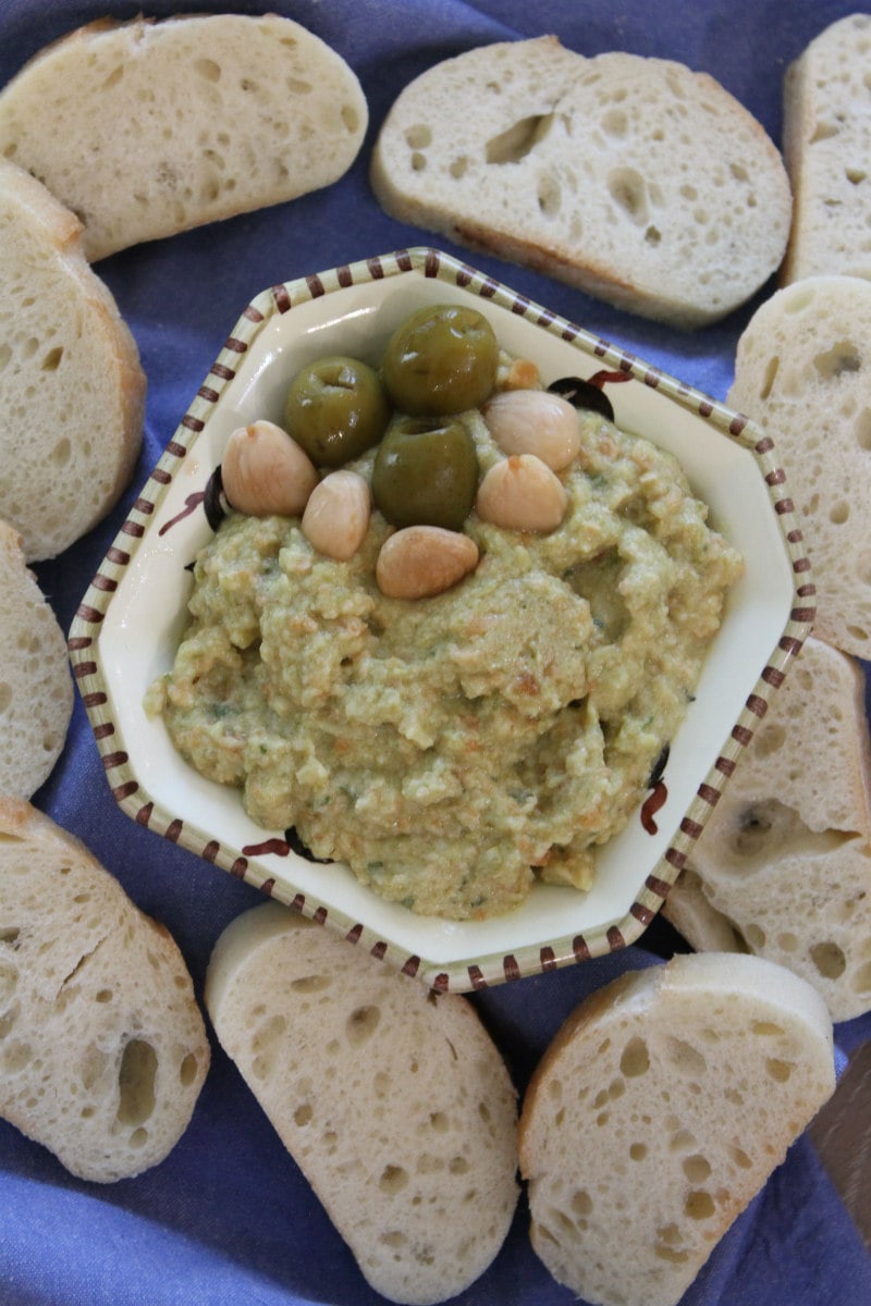 overhead shot of dish of green olive spread surrounded by baguette slices