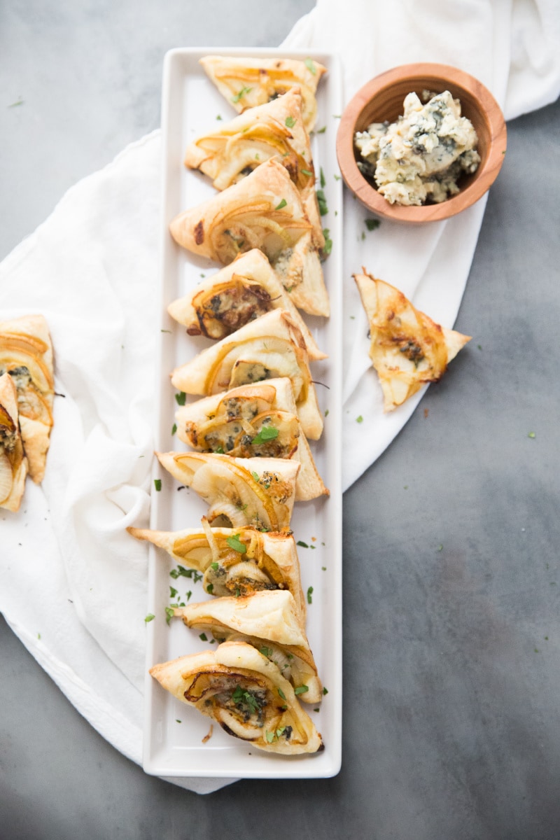 pear and blue cheese pastry triangles displayed on a white platter