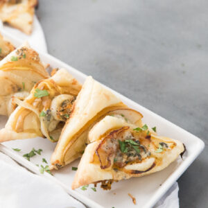 pear and blue cheese pastry triangles on a white platter