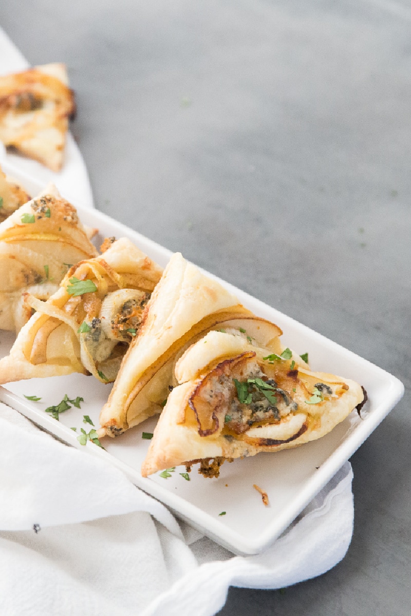 pear and blue cheese pastry triangles on a white platter