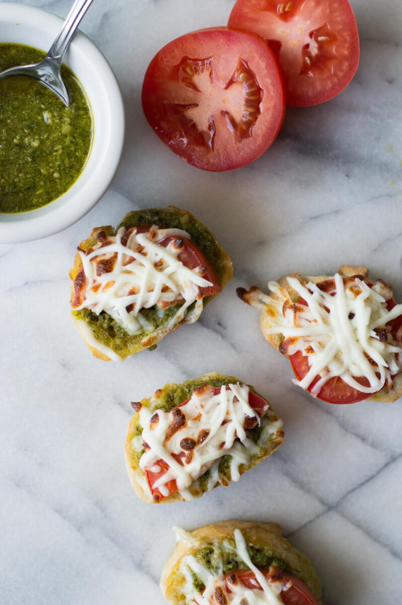 pesto pizza appetizers with bowl of pesto and tomato