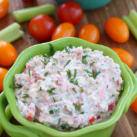 pine nut and feta cheese dip in a green dish surrounded by veggies