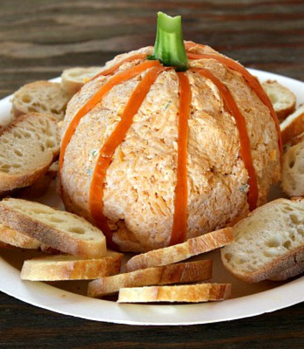 Pumpkin cheese ball on a white plate with baguette slices