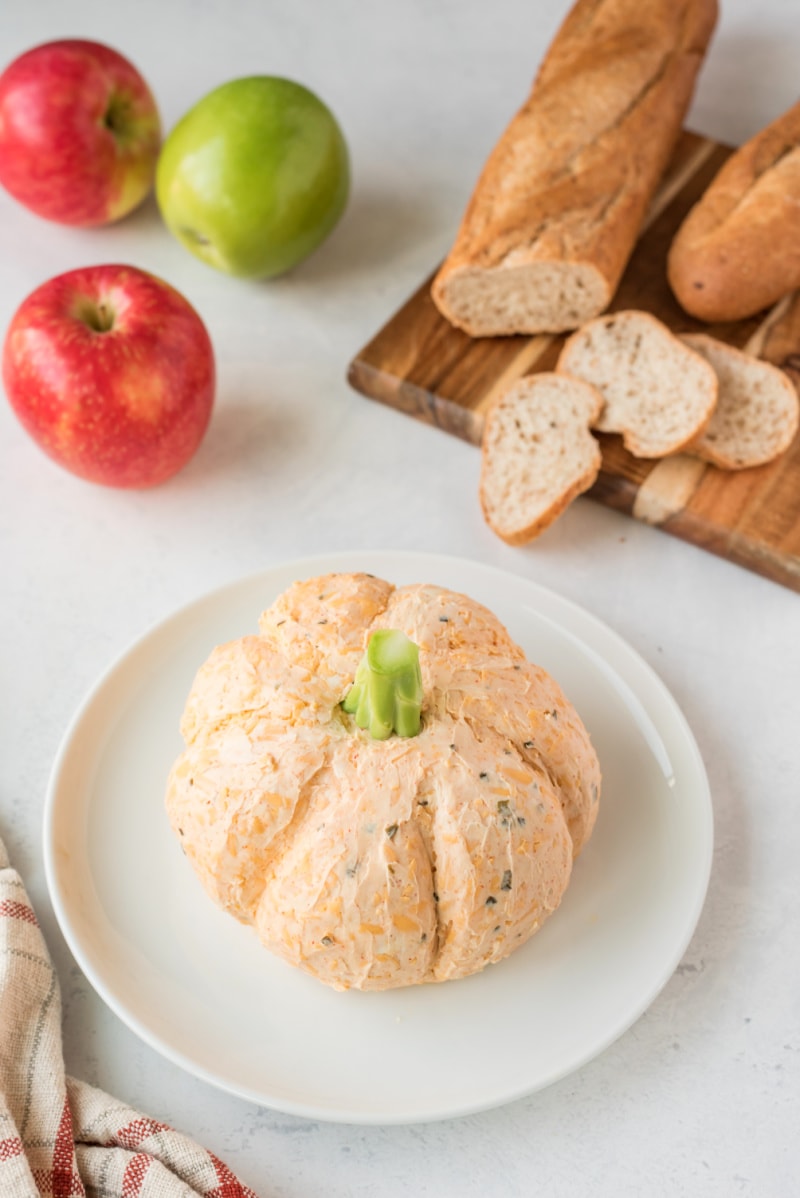 pumpkin cheese ball on a plate with apple and baguette