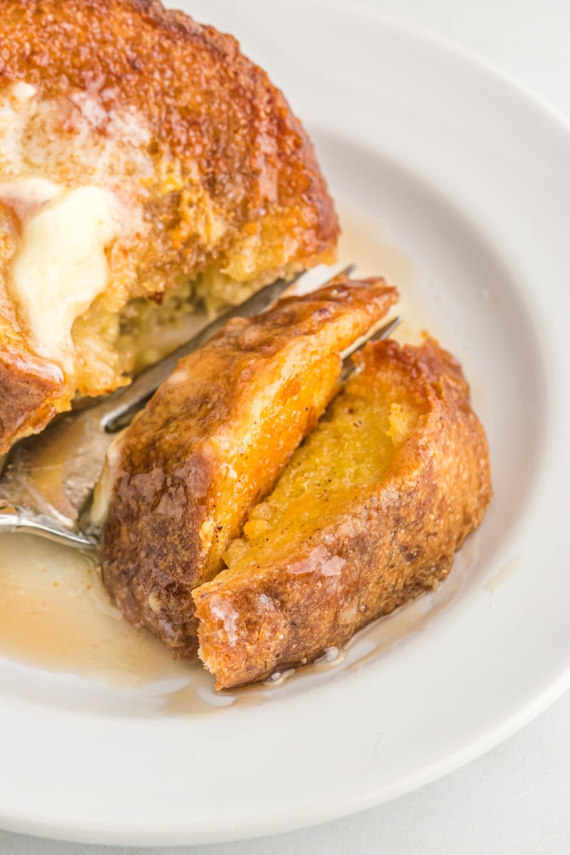 fork cutting into french toast covered with syrup