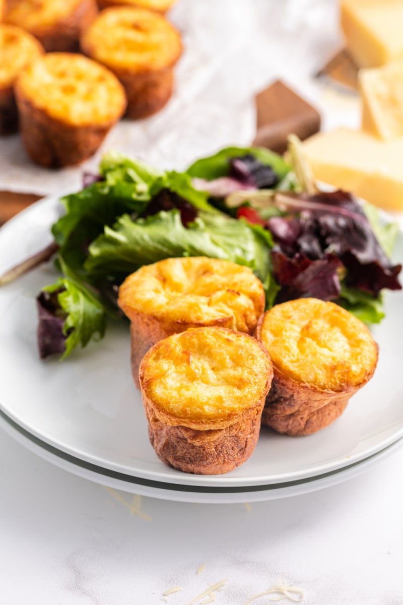 three cheese popovers on a plate with salad
