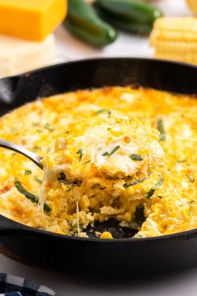 spooning mexican cheese souffle out of cast iron skillet