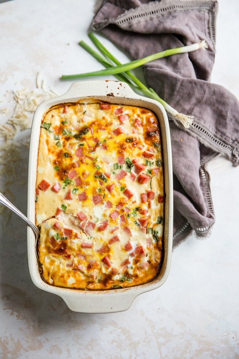 Overhead shot of Farmer's Casserole in a white casserole dish with a gray napkin and green onions