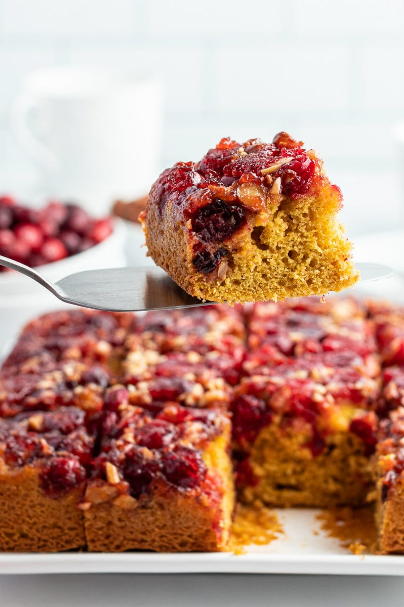 spatula showing slice of cranberry upside down cake above rest of cake