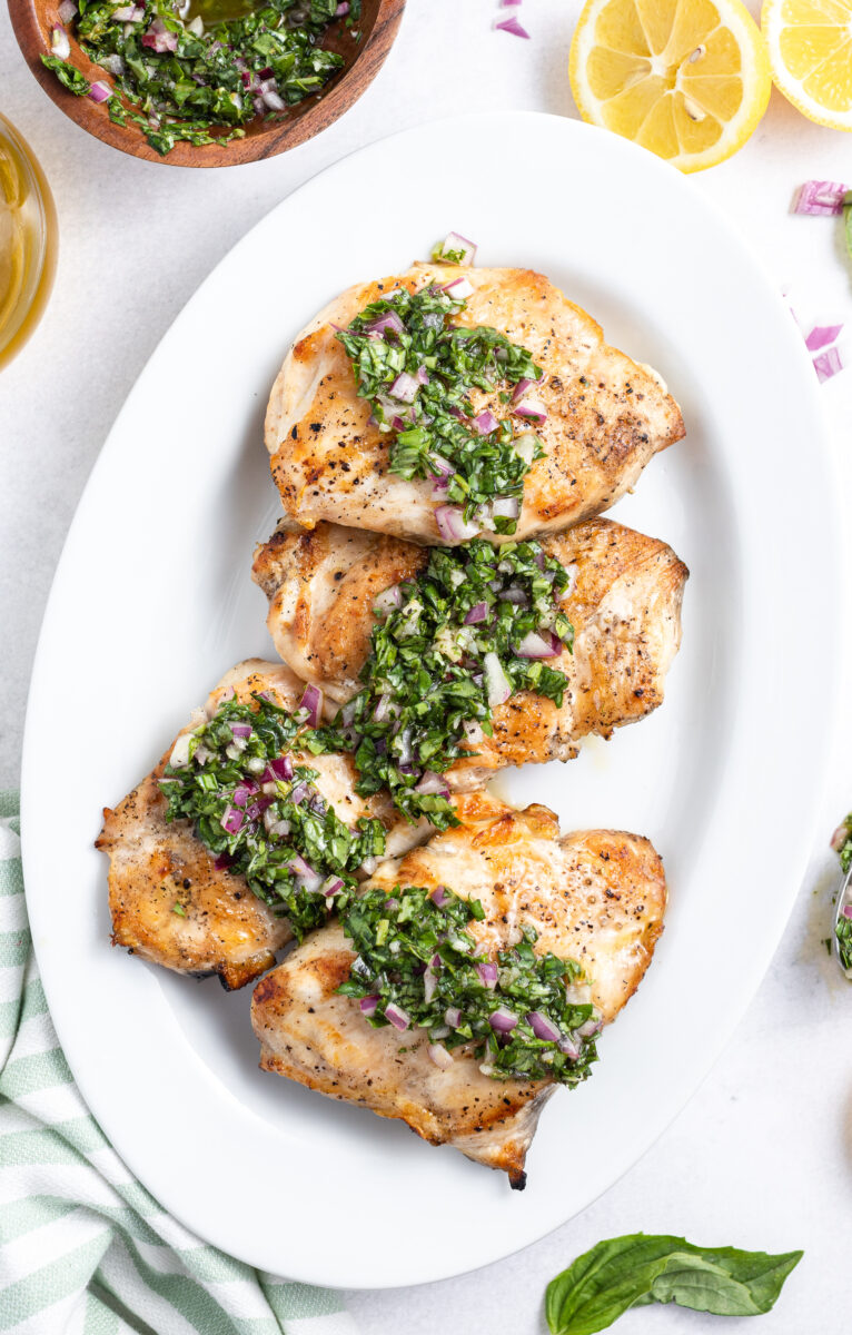 grilled chicken with basil chimichurri on a white platter