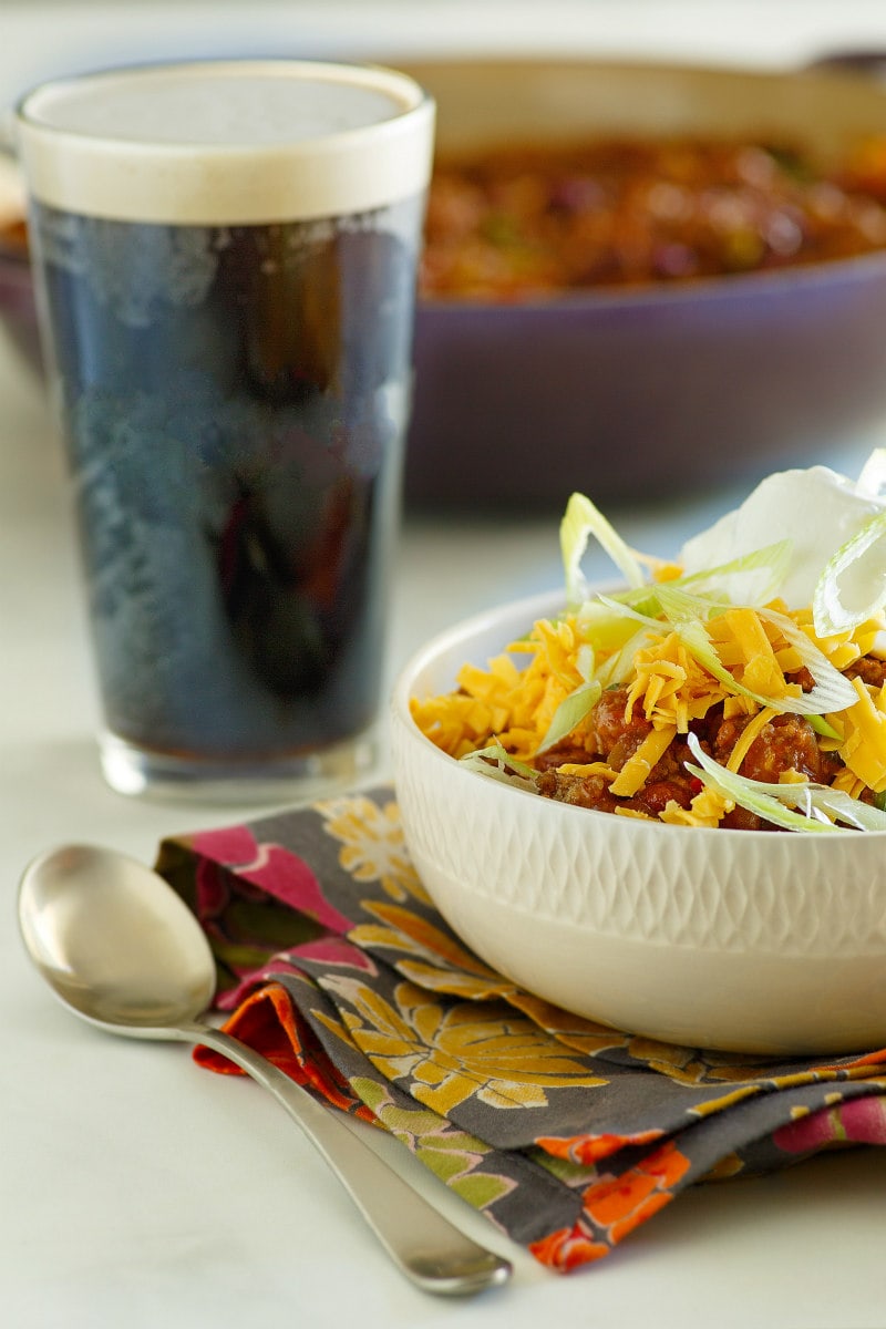 Beef and Dark Beer Chili recipe from RecipeGirl.com #beef #dark #beer #darkbeer #chili #recipe #RecipeGirl #super #bowl #superbowl #party Bowl of Beef and Dark Beer Chili with a glass of dark beer