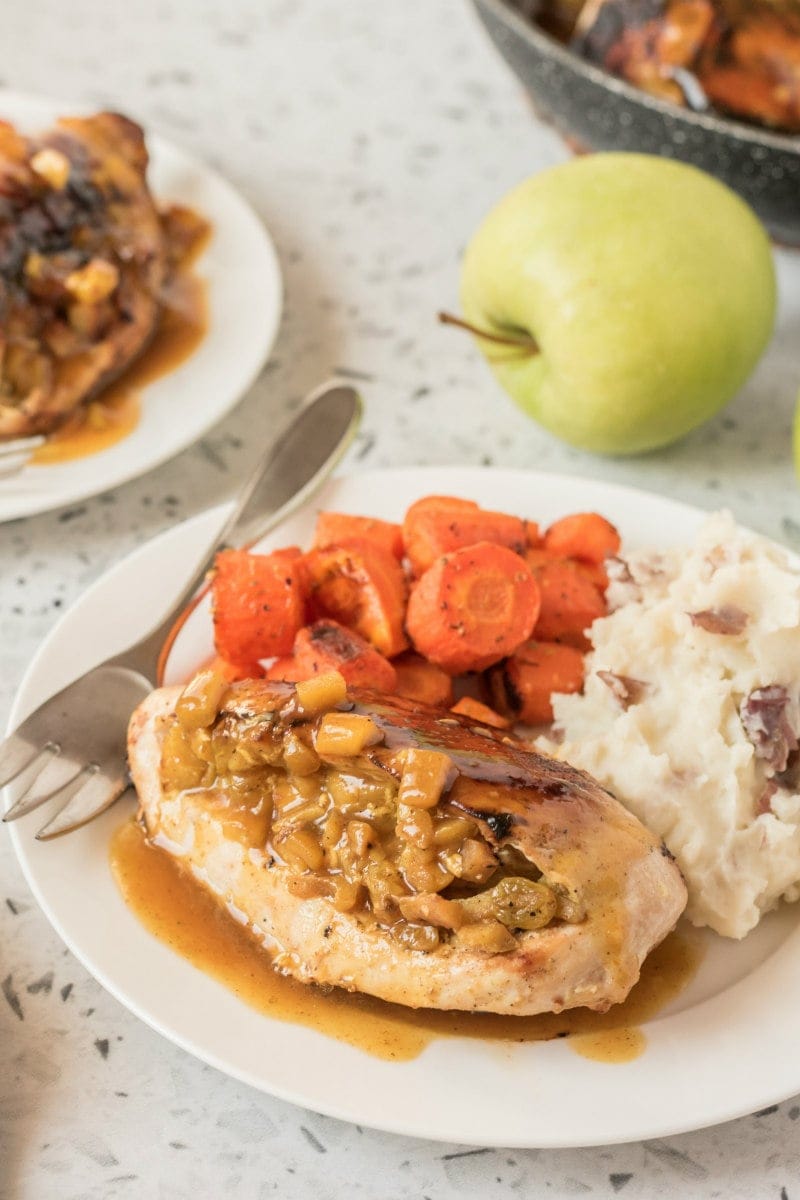 chicken breasts with curried apple stuffing on a plate with potatoes and carrots