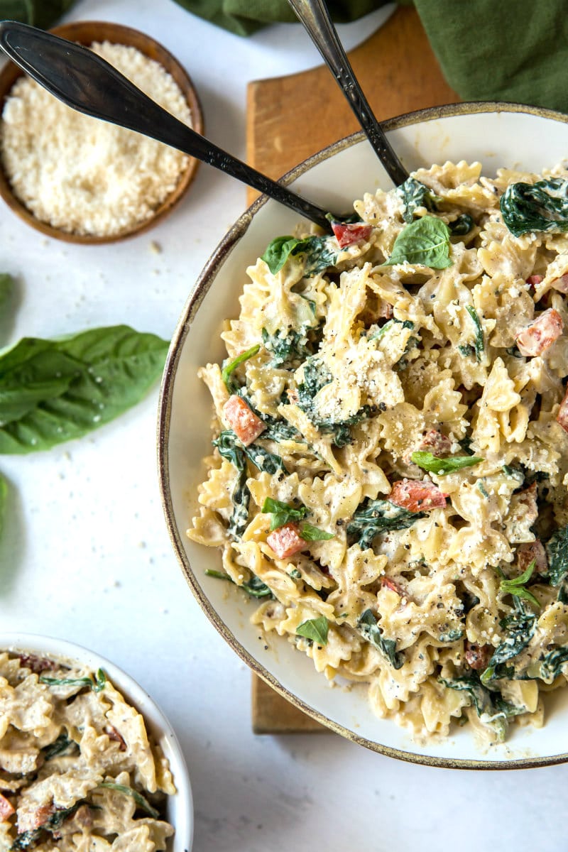 bowl of farfalle pasta with spinach and ricotta cheese with a side of parmesan cheese