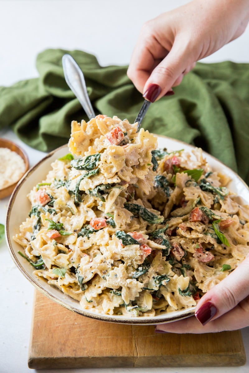 serving from bowl of farfalle pasta with green cloth napkin decor