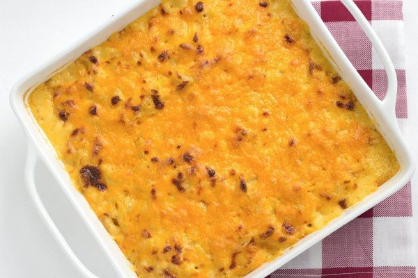 overhead shot of white casserole dish of macaroni and cheese with red/white plaid napkin underneath