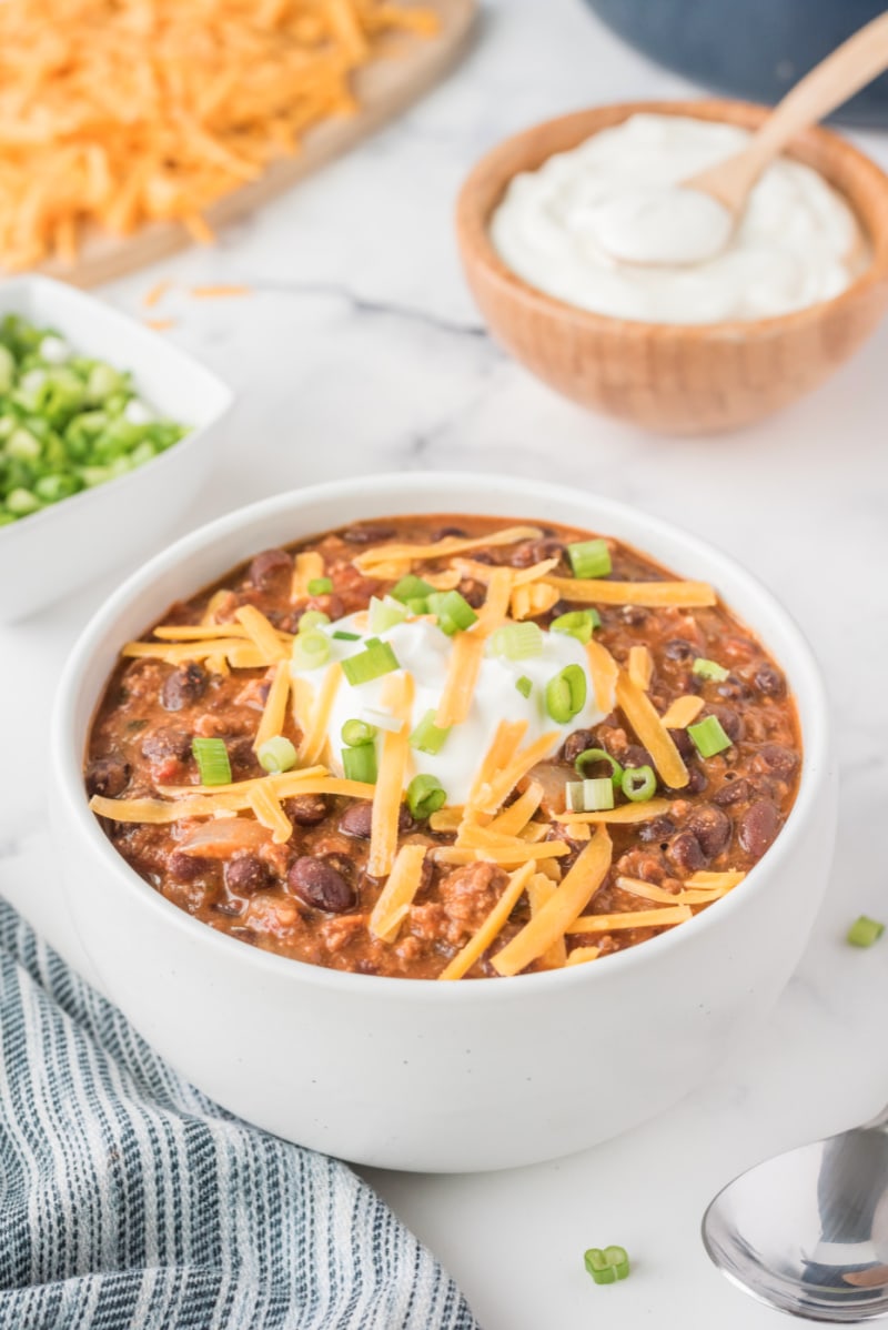 white bowl of chili with cheese on top