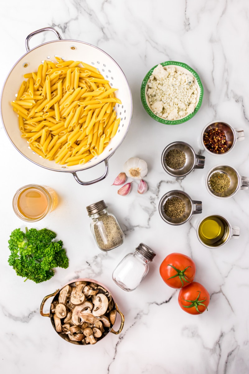 ingredients displayed for making penne with mushrooms tomato and gorgonzola cheese