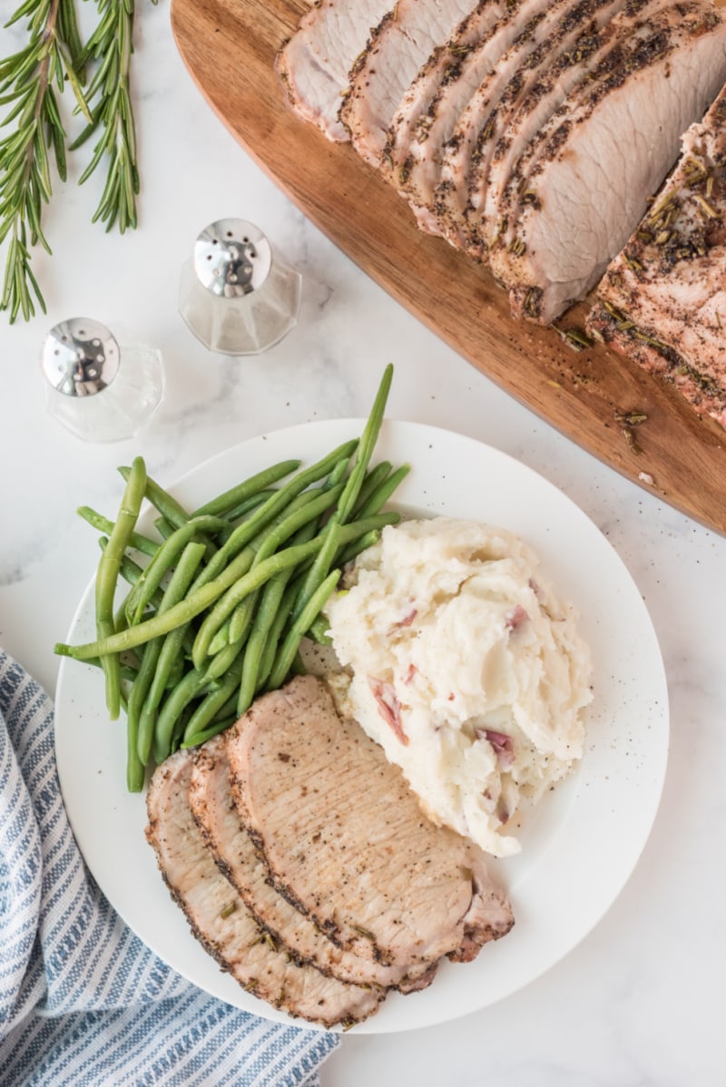 sliced pork roast on plate with green beans and potatoes