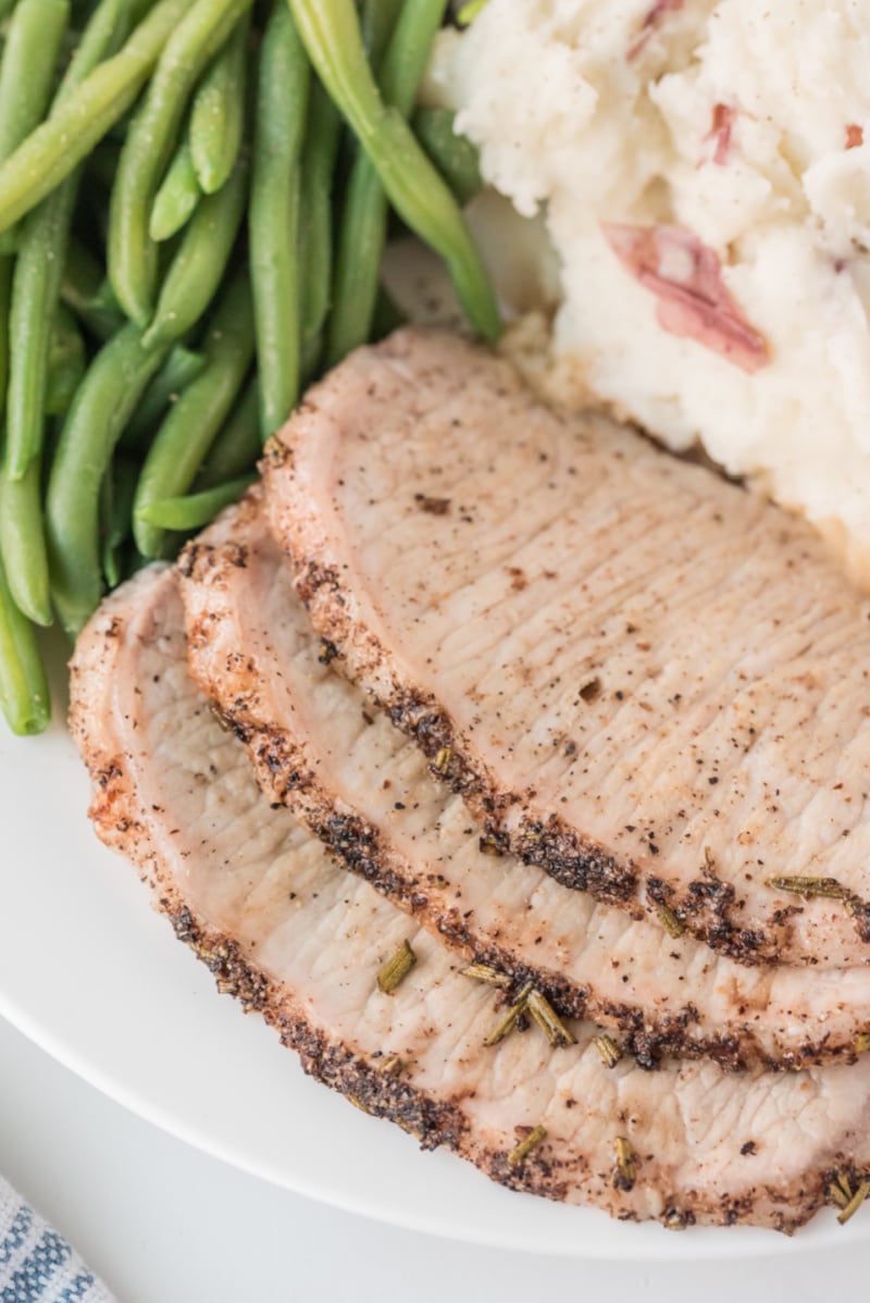close up slices of pork roast served with green beans