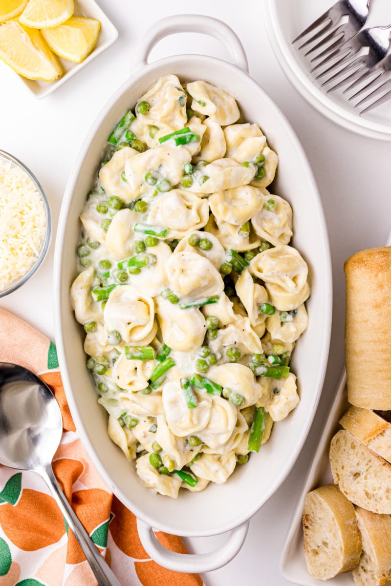 Tortellini, Peas and Asparagus with Creamy Tarragon Sauce in a white casserole dish