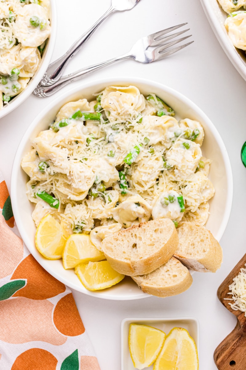 Tortellini, Peas and Asparagus with Creamy Tarragon Sauce in a bowl with bread and lemon