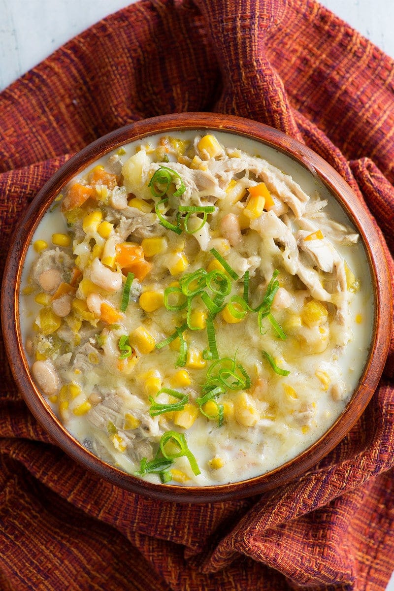 overhead shot of Bowl of White Chicken Chili in orange bowl set on orange cloth napkin