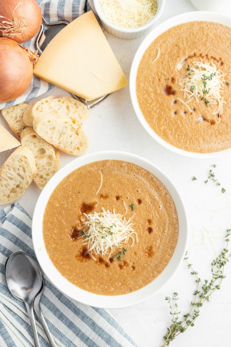 caramelized onion soup in white bowls with bread on side