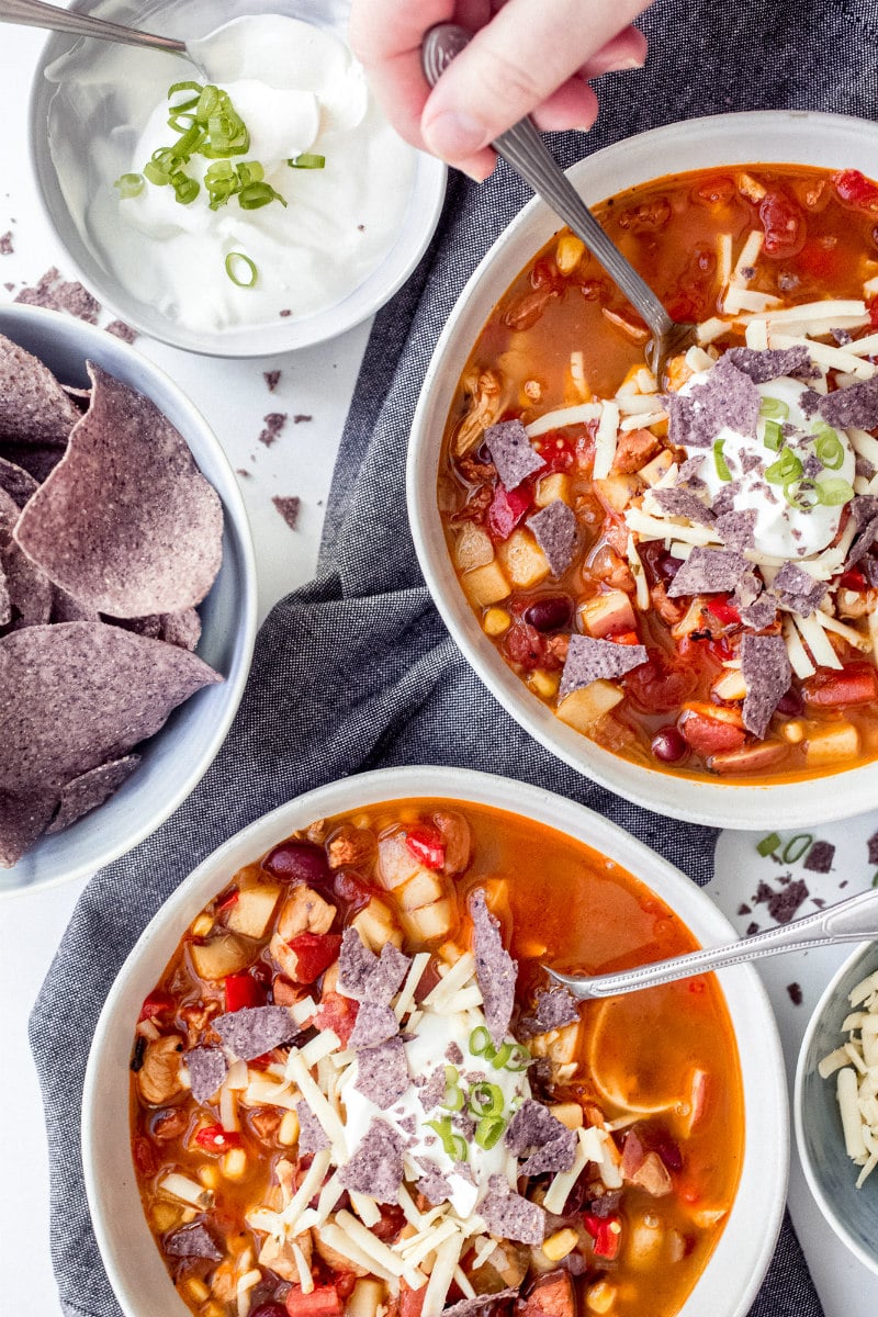 bowls of chicken tortilla sausage soup with garnishes