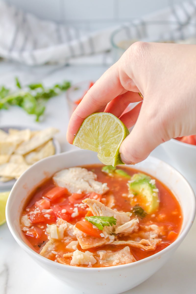 squeezing lime onto chicken tortilla soup