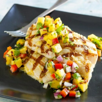 Grilled Mahi Mahi topped with Grilled Pineapple Salsa on a black plate