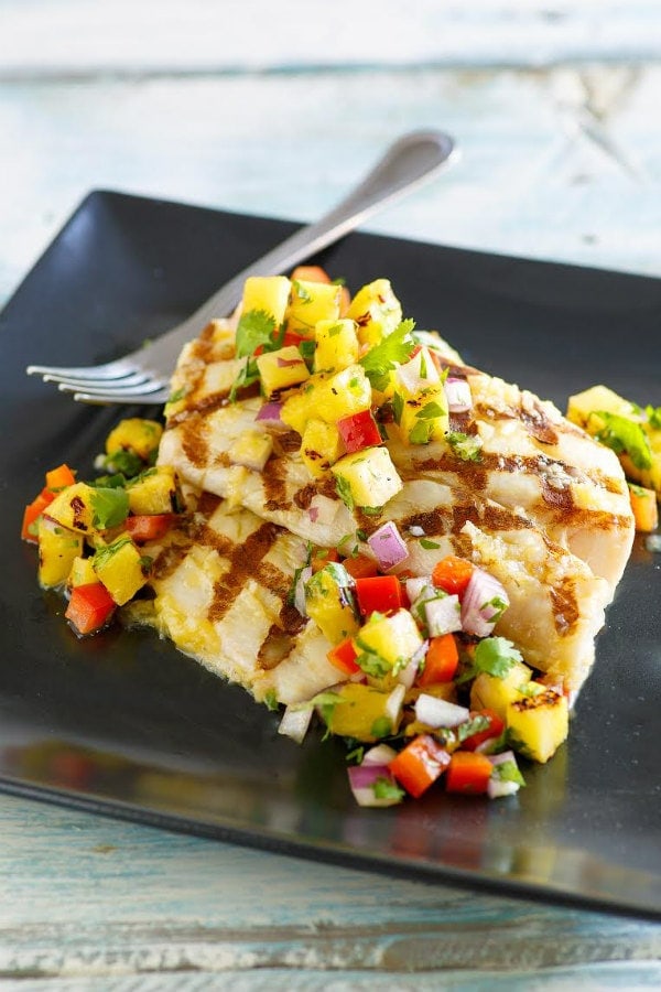 Grilled Mahi Mahi topped with Grilled Pineapple Salsa on a black plate