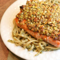 pistachio baked salmon served over pasta on a white plate