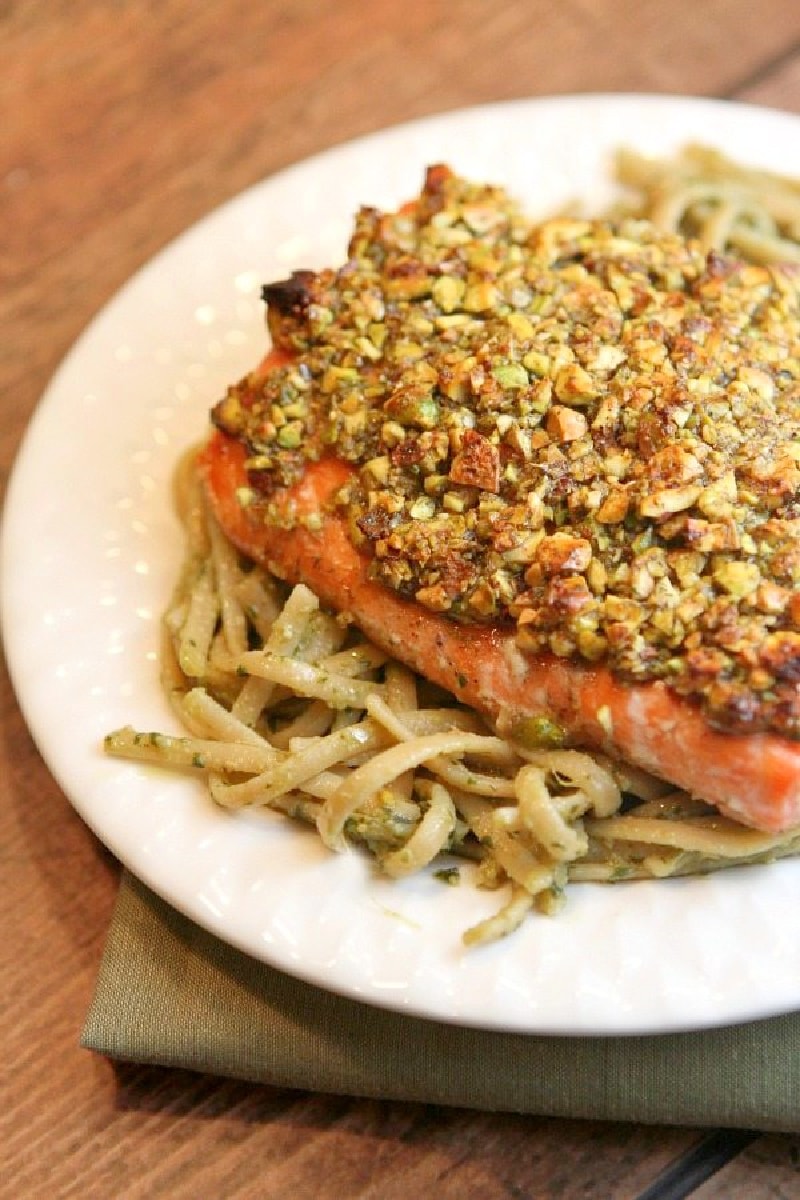 pistachio baked salmon served over pasta on a white plate