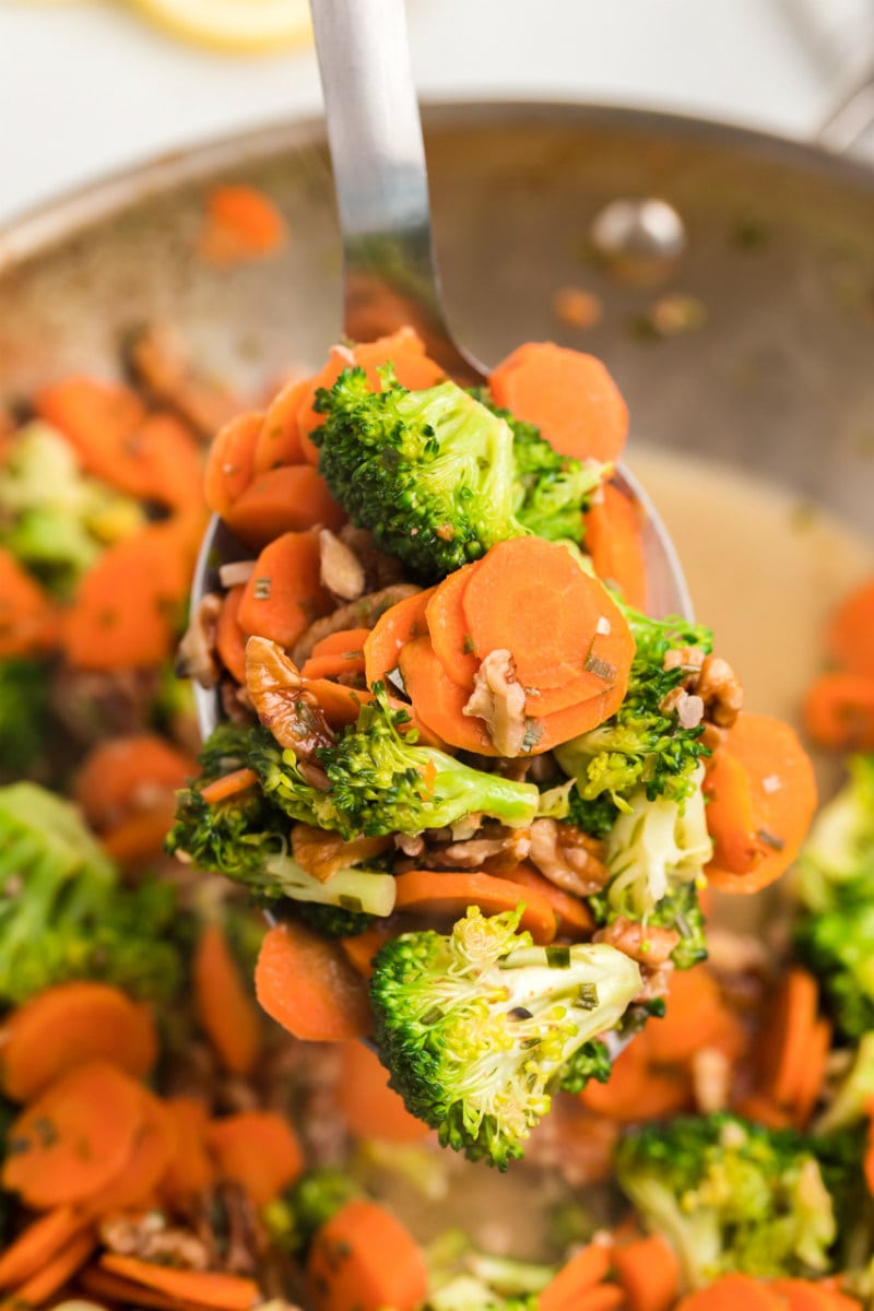 spoonful of sauteed broccoli with carrots and pecans