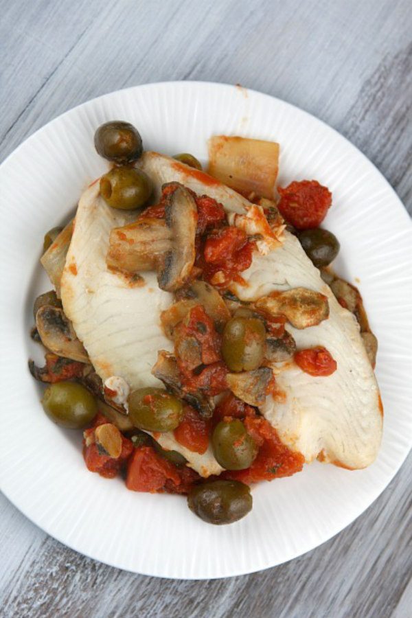 Tilapia with Olive, Mushroom and Tomato Sauce on a white plate