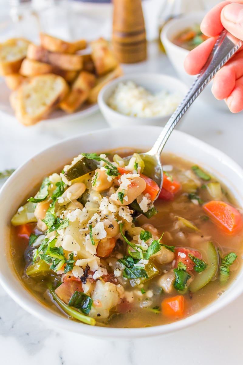 spooning out tuscan vegetable soup out of bowl