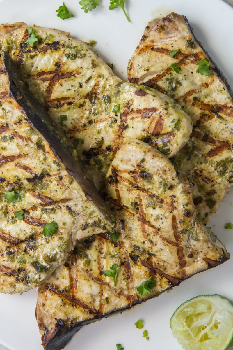 grilled swordfish on a white plate with a lime