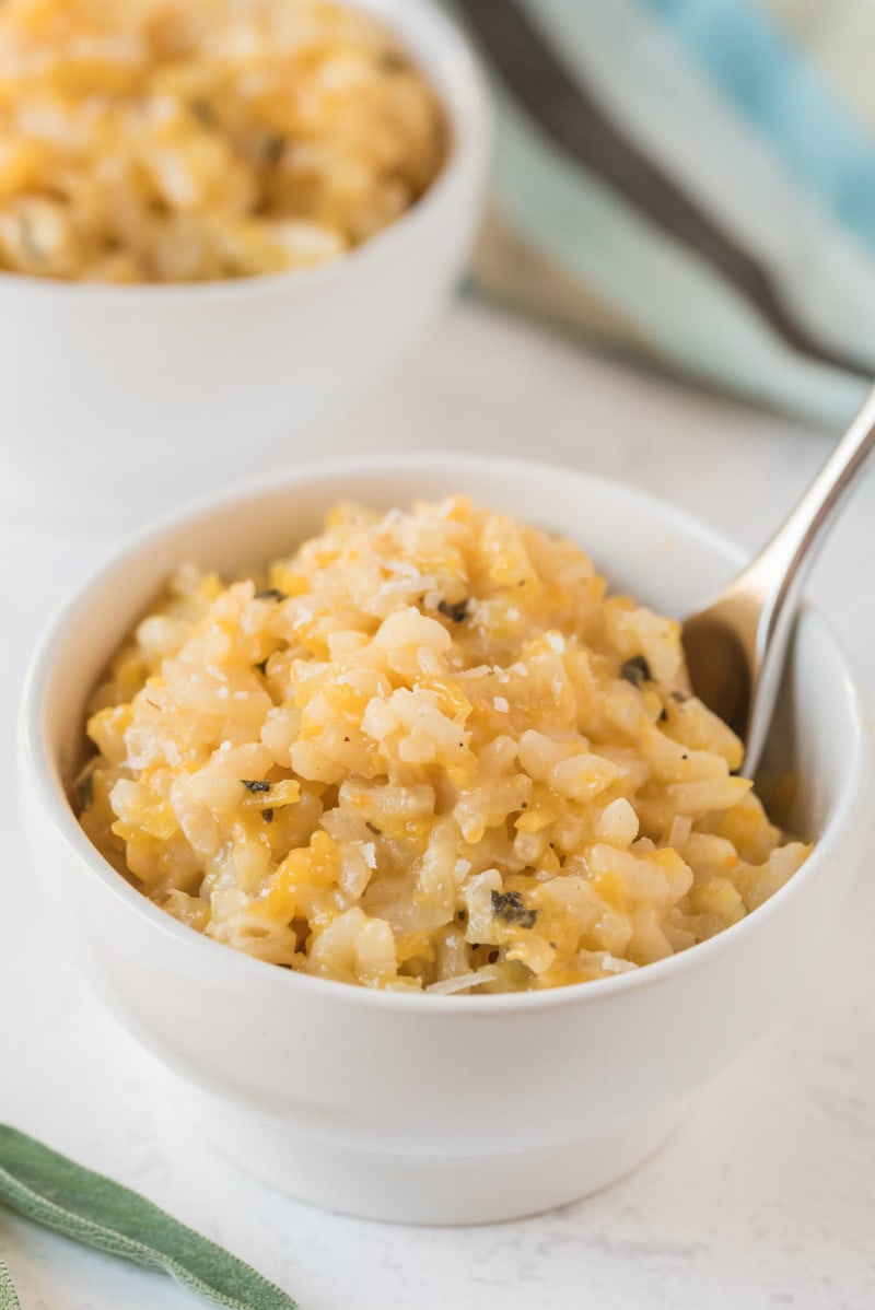 butternut squash risotto in a white bowl with a spoon