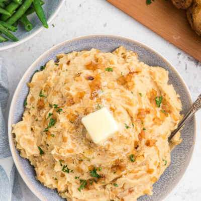 caramelized onion and horseradish mashed potatoes in a bowl with a pat of butter