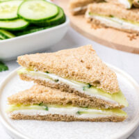 two goat cheese finger sandwich halves stacked on white plate