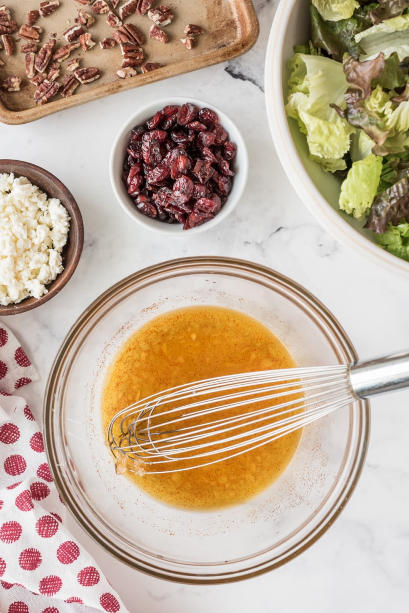 salad dressing in bowl and salad fixings on side