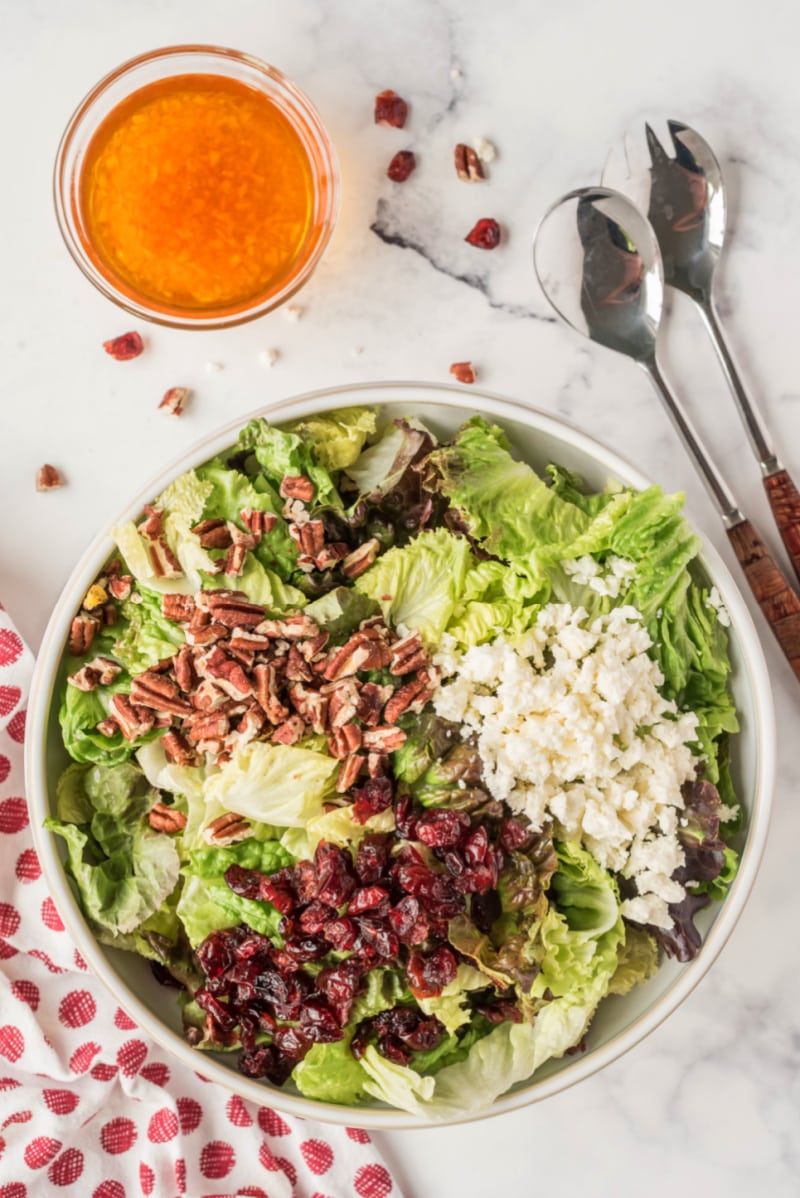 ingredients in bowl for making mixed green salad with apple cider vinaigrette