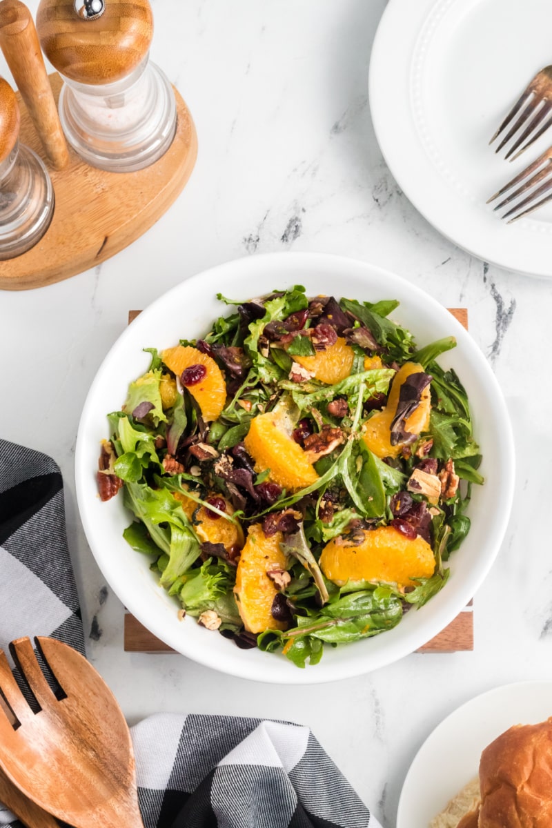 mixed green salad with oranges and dried cranberries in white bowl