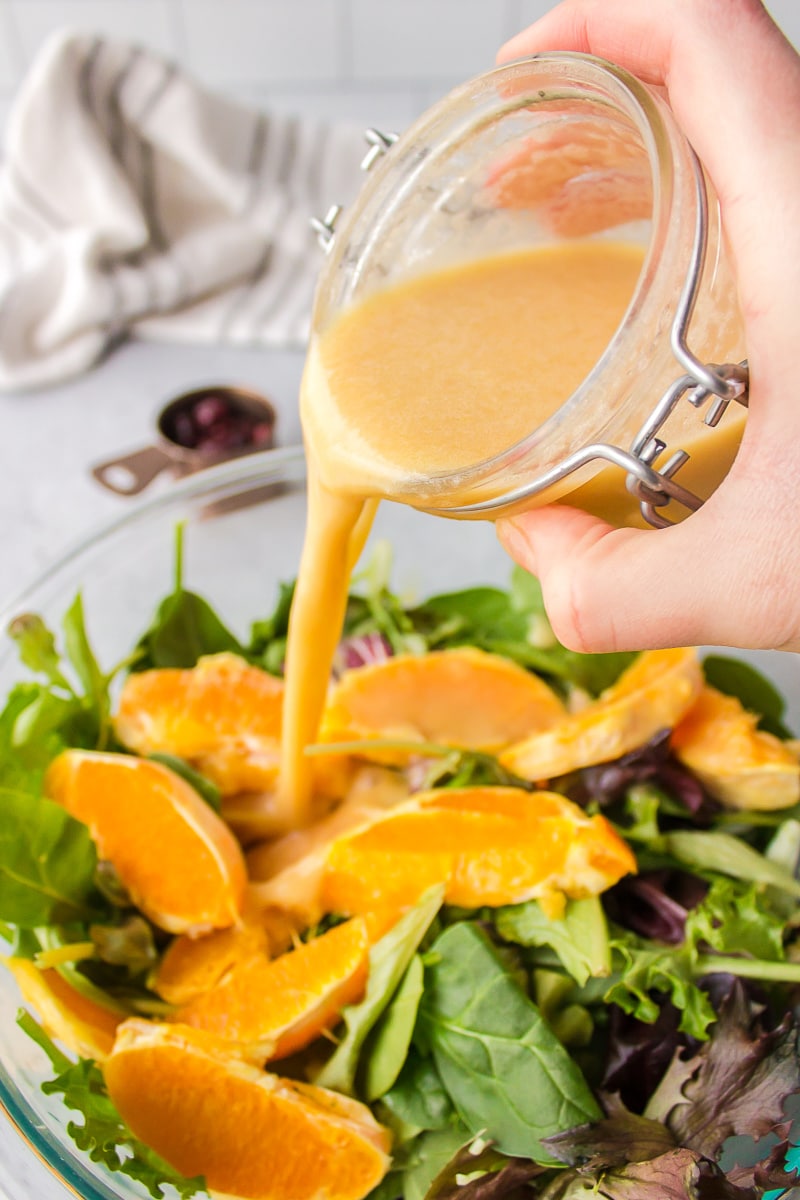 pouring dressing onto citrus salad