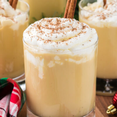spiked eggnog in a glass mug with whipped cream and cinnamon stick