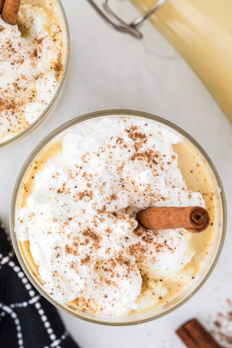 overhead shot of eggnog with whipped cream and cinnamon stick