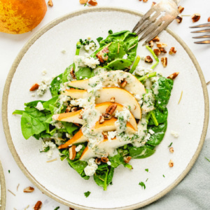 spinach and pear salad on white plate with fork